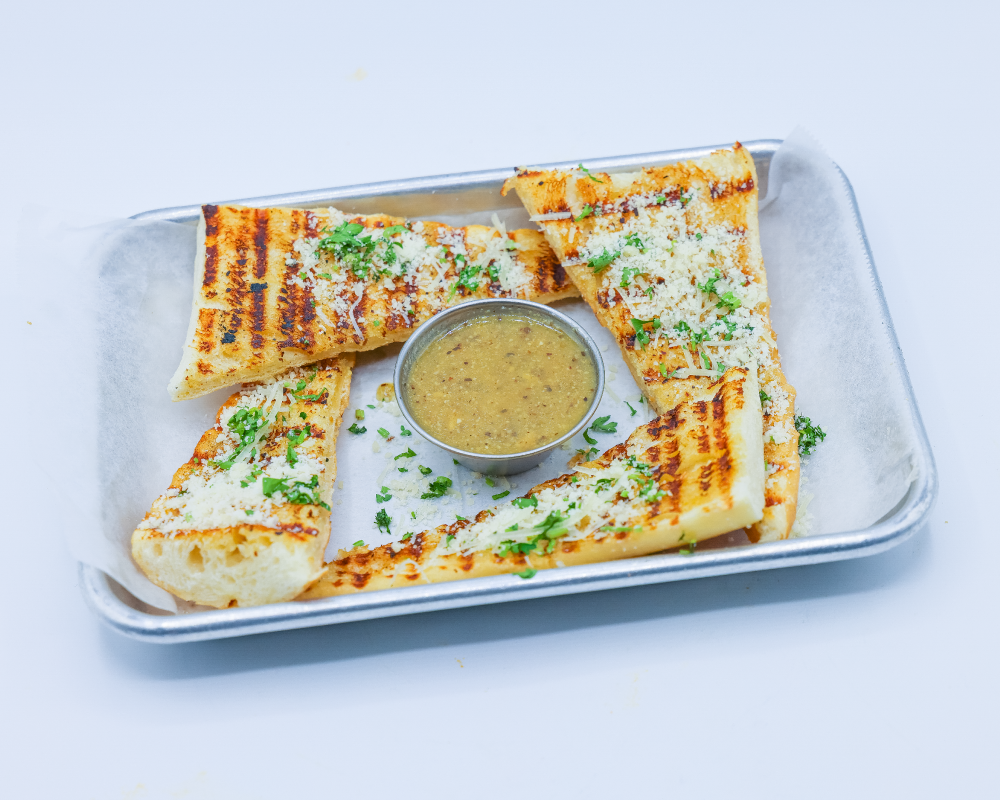 Grilled garlic bread with cilantro dipping sauce topped with cheese and cilantro